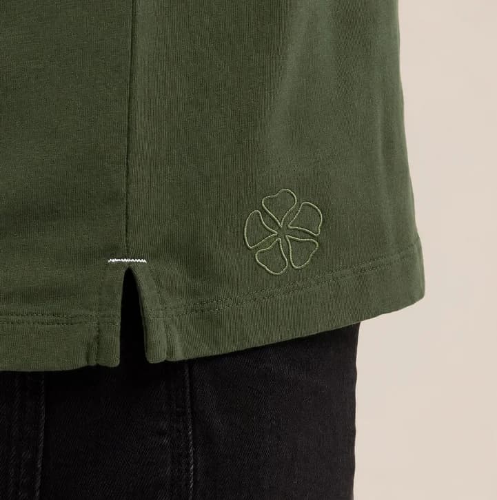 Símbolo floral de Jaze bordado sobre una prenda verde